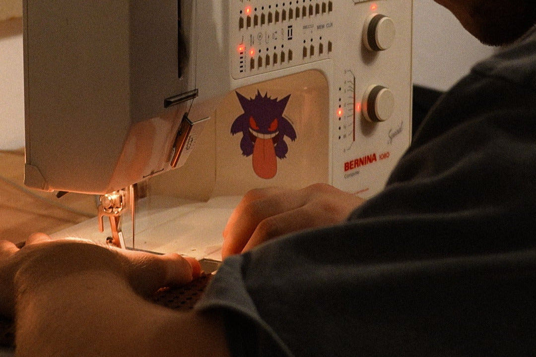 Person using a sewing machine with headphones on, in a home setting.